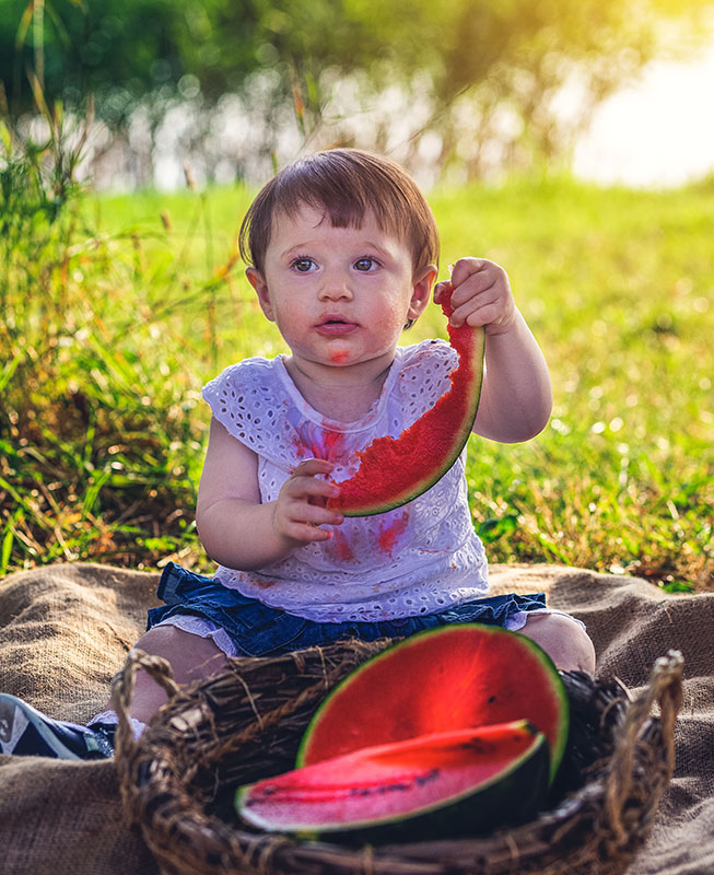 bambina che si sporca mangiando un anguria